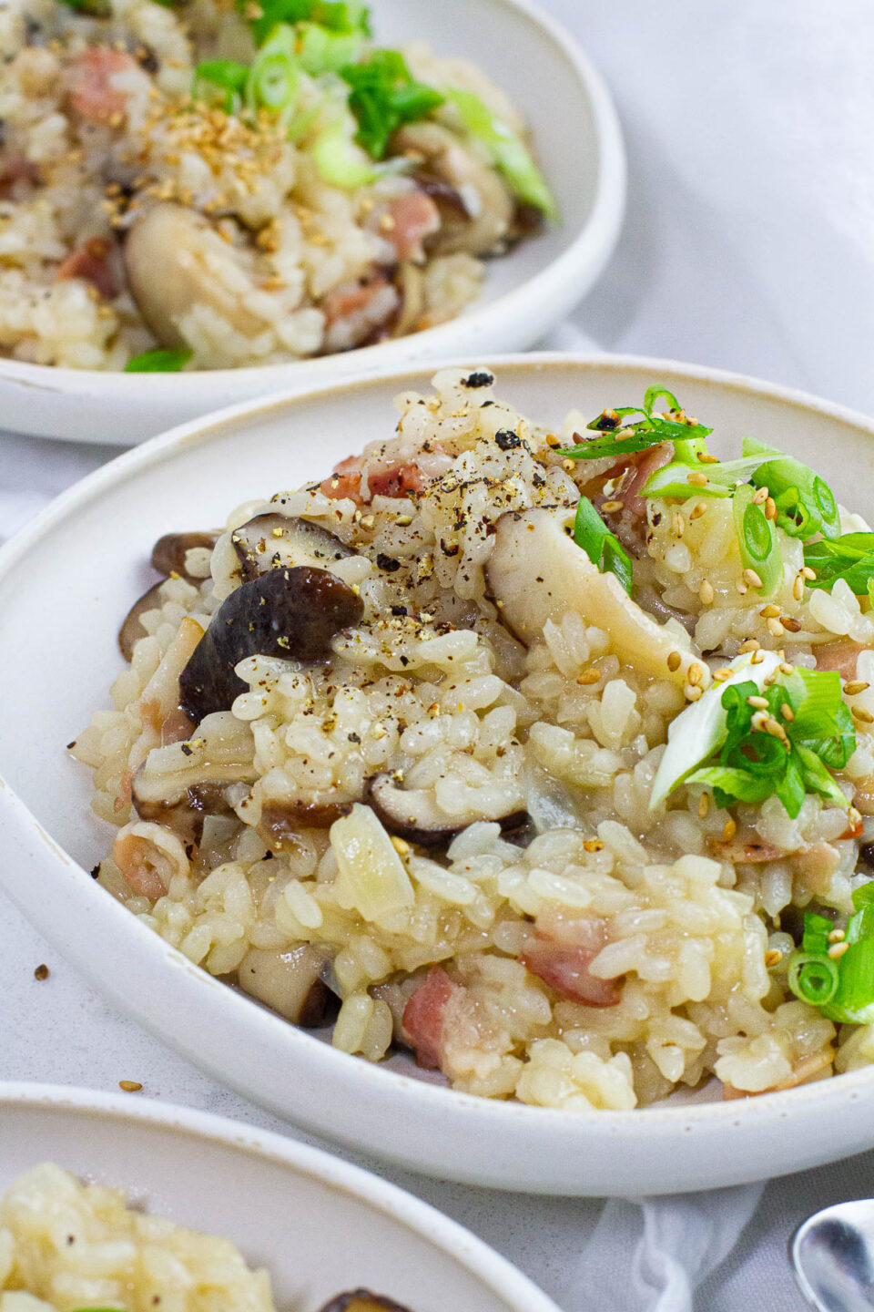 Close up shot of bacon mushroom risotto with scallion topping.