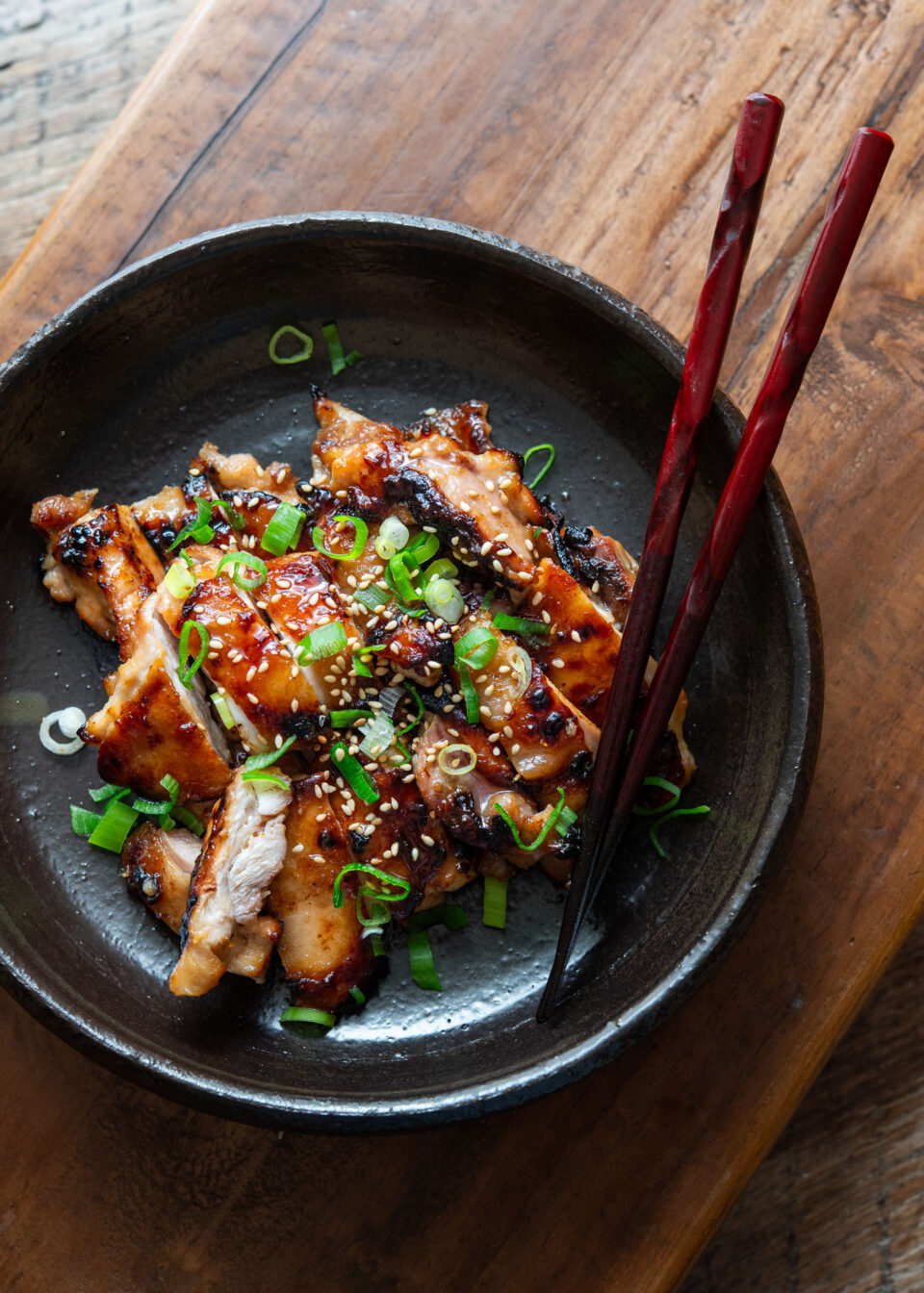 A plate of miso chicken thighs with chopsticks.