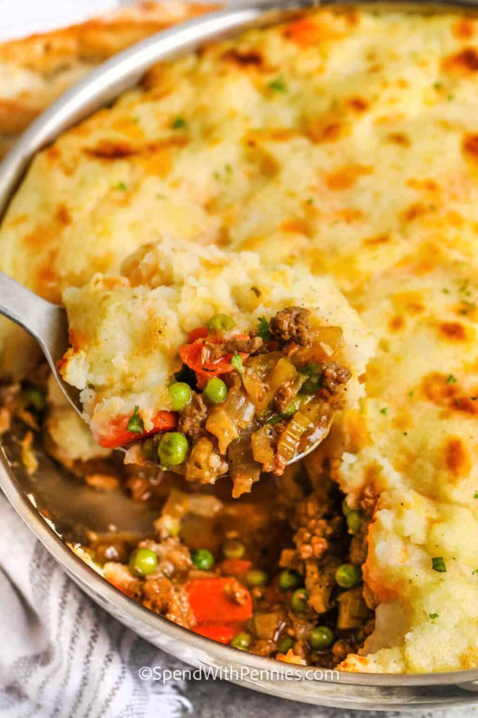 baked cottage pie in a pan with a spoonful being taken out