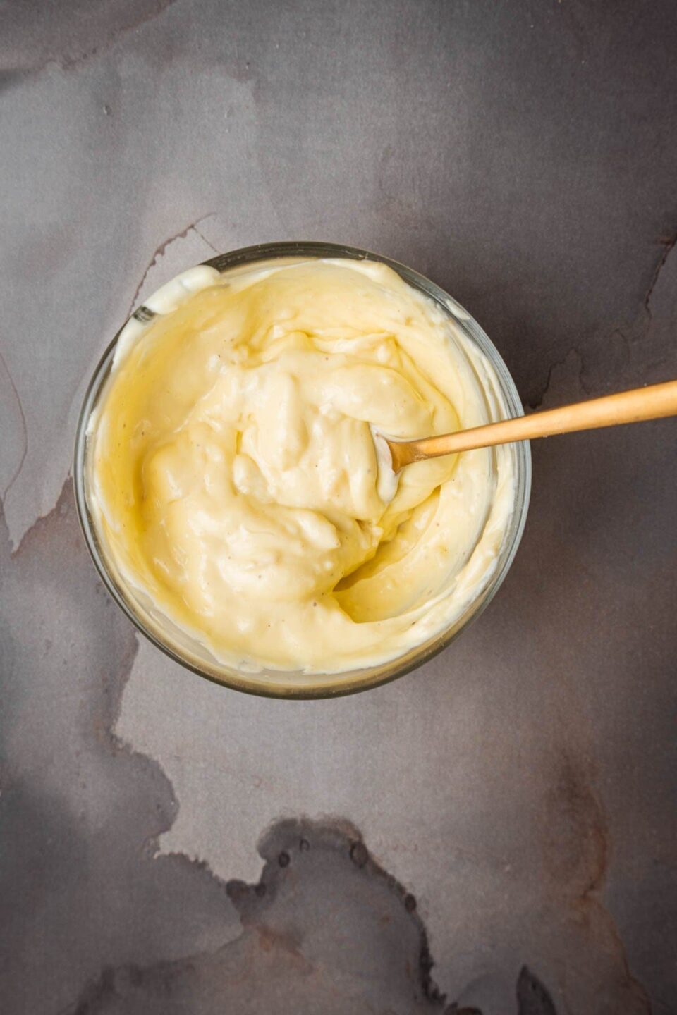 A bowl of roasted garlic aioli with a wooden spoon.
