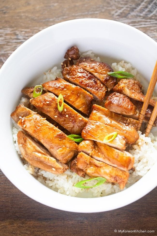 Sliced teriyaki chicken on rice with chopsticks on the side.